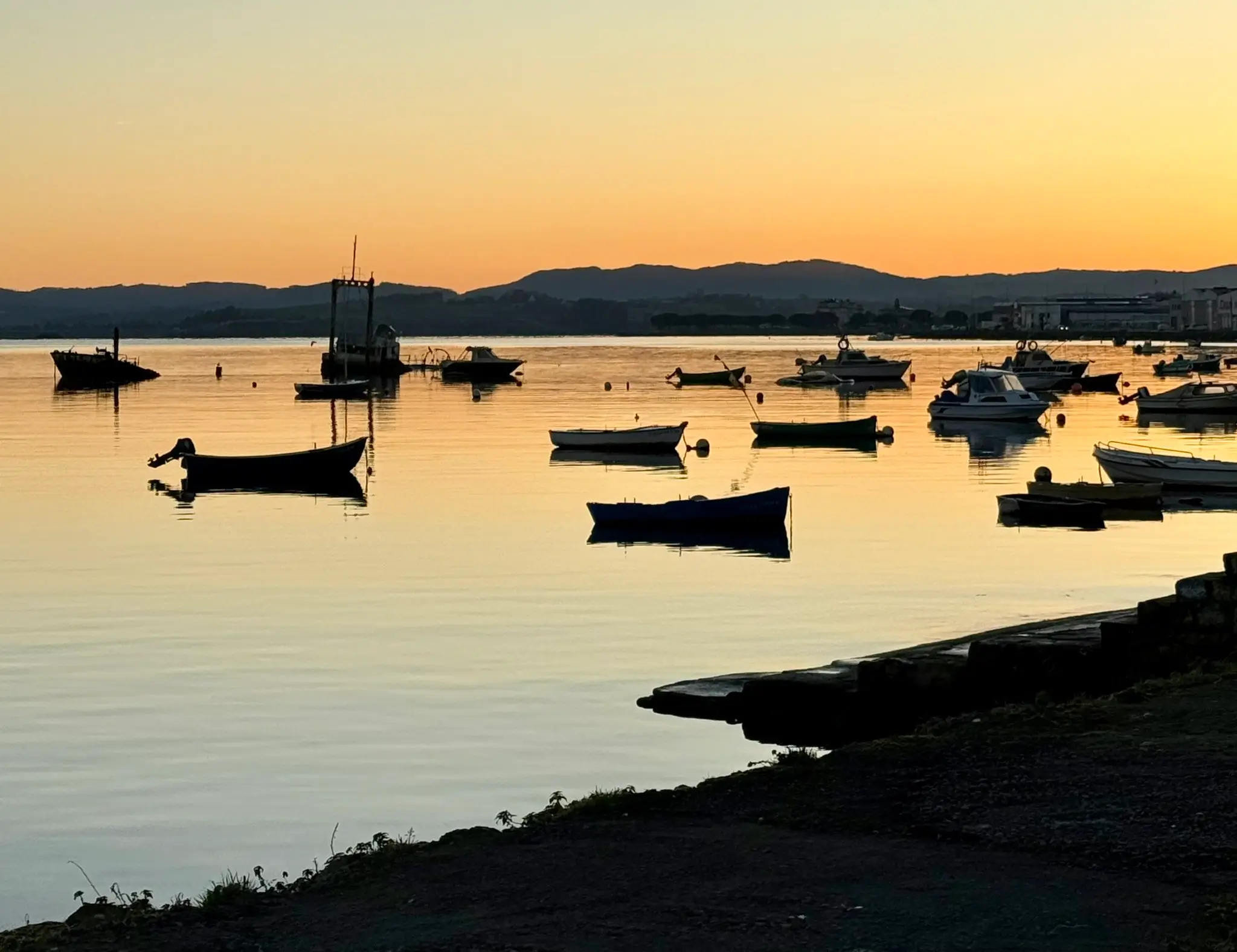 Fishing boats on a calm Mediterranean sea at sunrise with golden sky and soft reflections