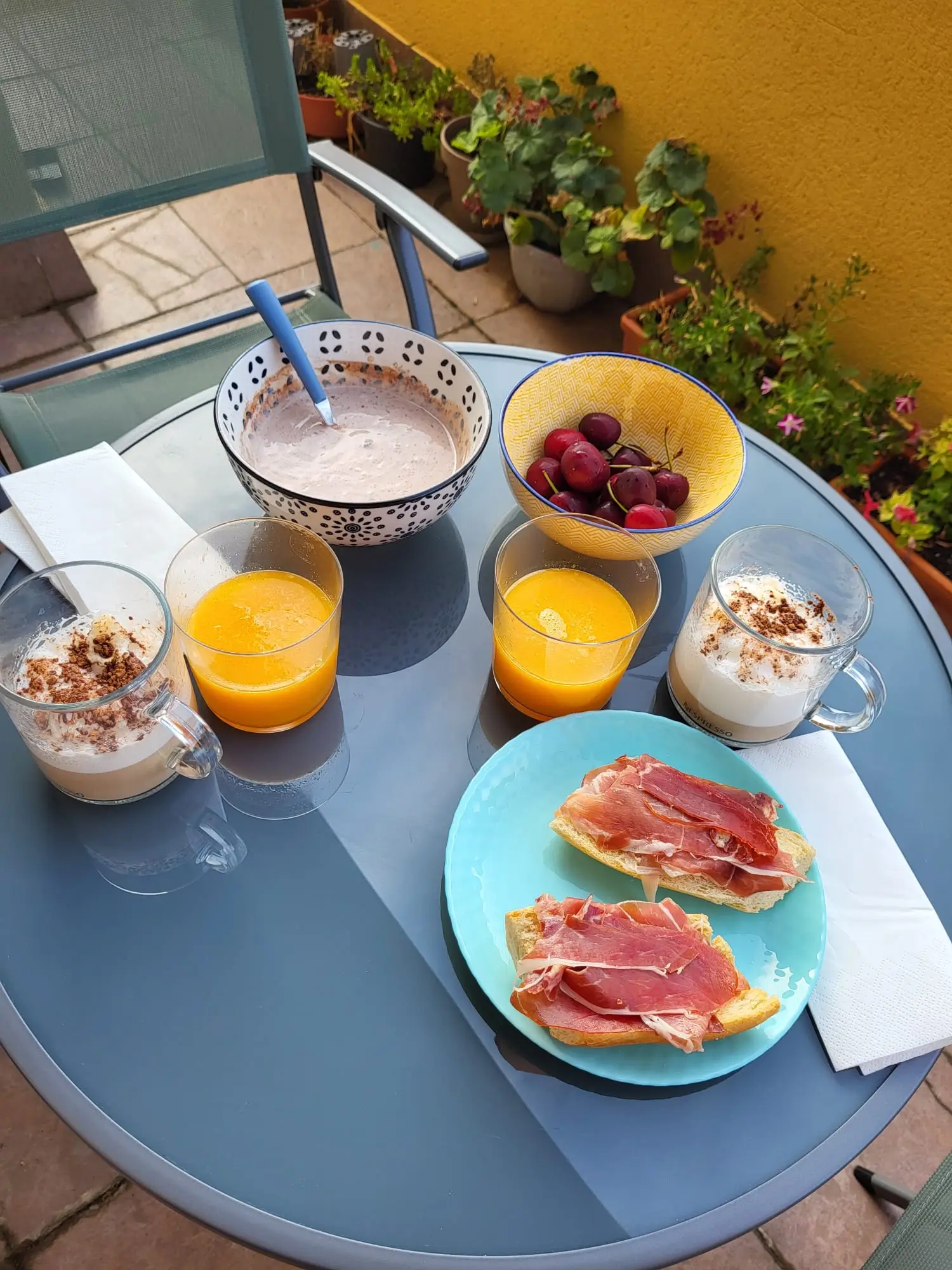 Traditional Mediterranean breakfast with jamón on bread, coffee with cinnamon, orange juice and fresh fruit on a sunny terrace