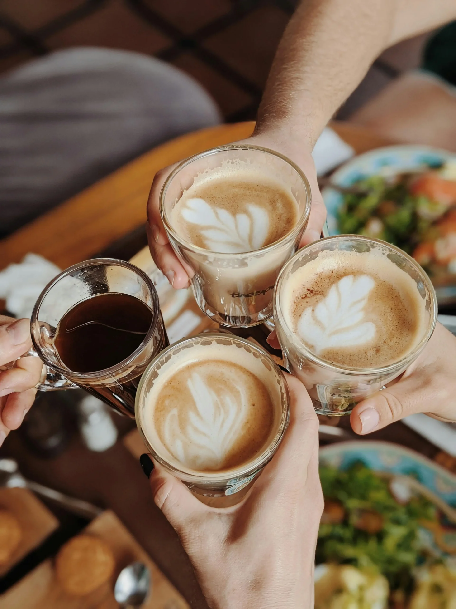 Friends toasting with Spanish Lattes and espresso at a cozy Mediterranean café table