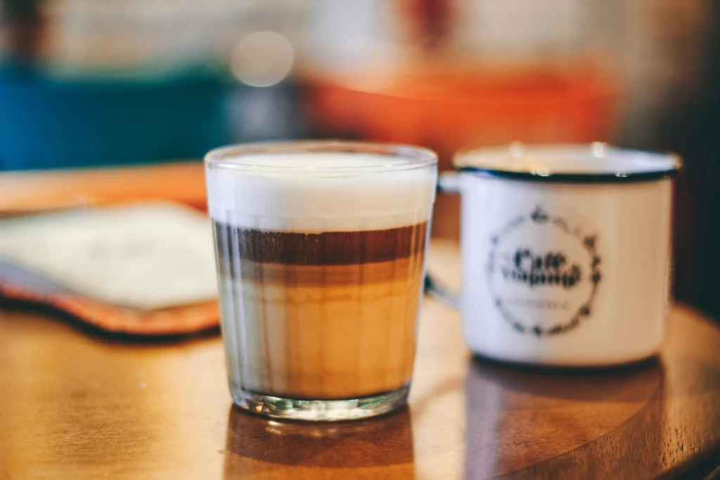 Glass of Spanish latte showing distinctive layers of espresso and condensed milk on wooden table